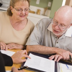 Senior Adult Couple Going Over Papers in Their Home with Agent.