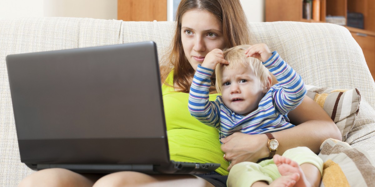 Smiling mother with baby working with computer at home