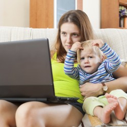 Smiling mother with baby working with computer at home