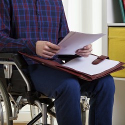 Young man on wheelchair reading documents at home