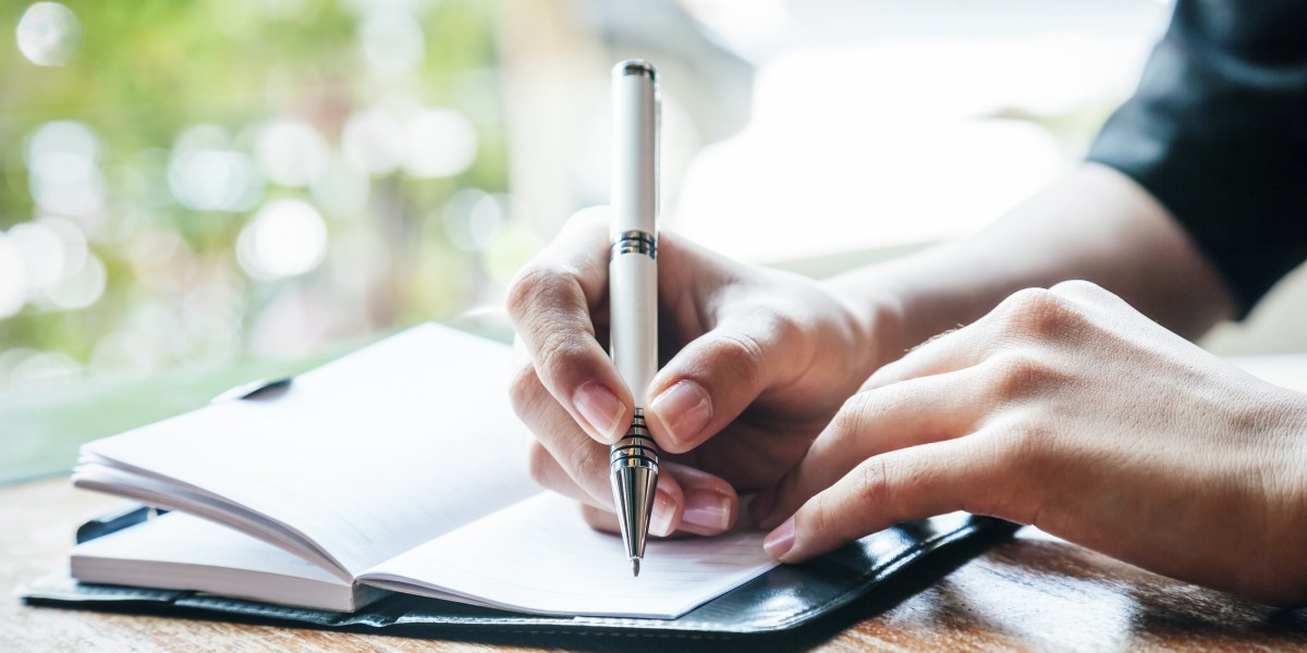 Person writing with white pen in notebook