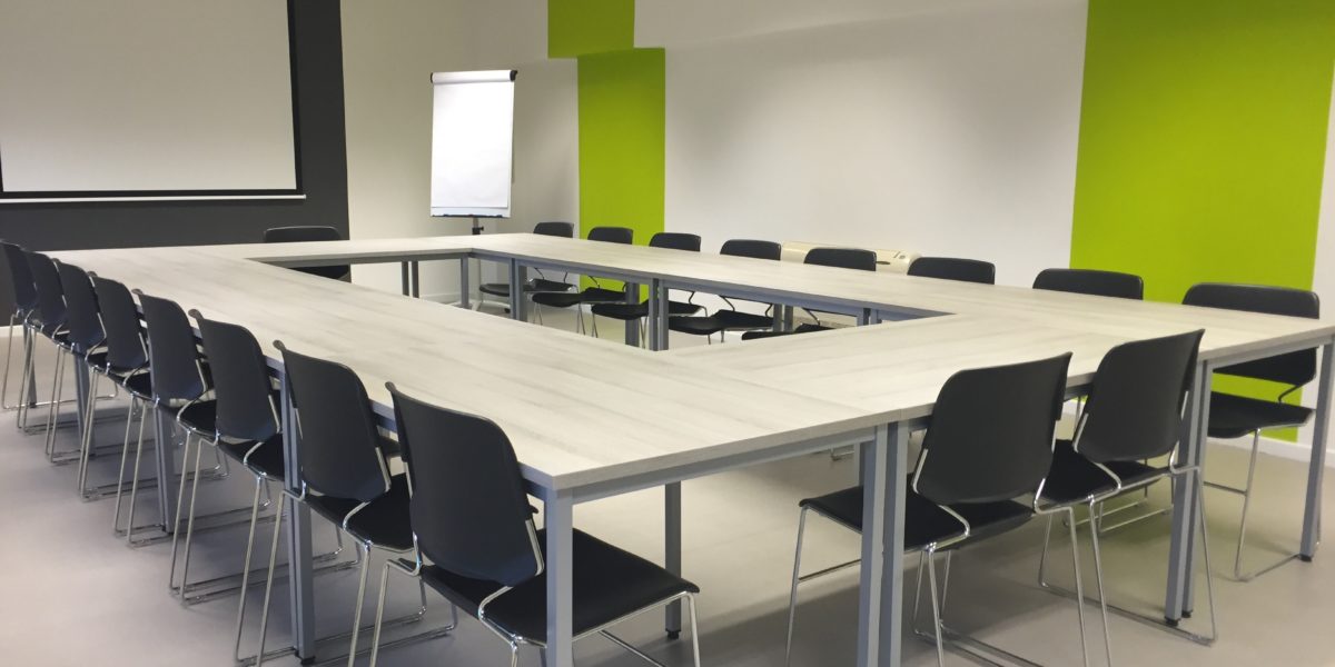 A room with green walls with a big table and chairs