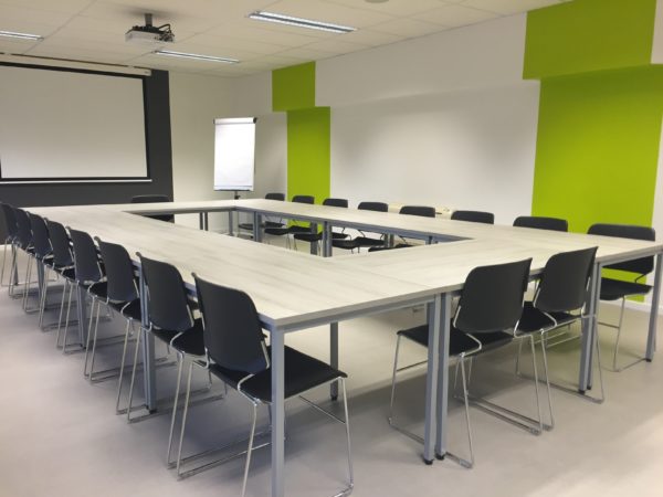 A room with green walls with a big table and chairs