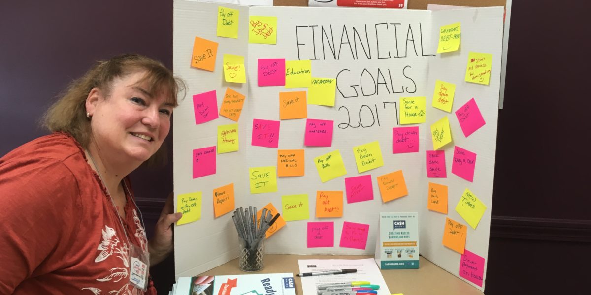 Woman beside poster with financial goals on sticky notes