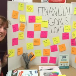 Woman beside poster with financial goals on sticky notes