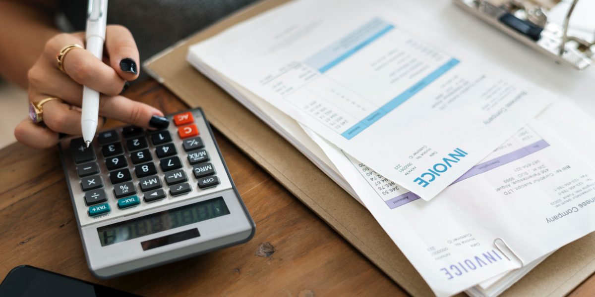 woman using calculator with bills