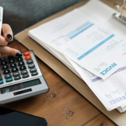 woman using calculator with bills