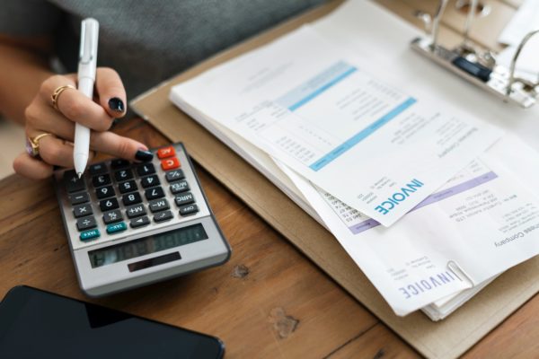 woman using calculator with bills