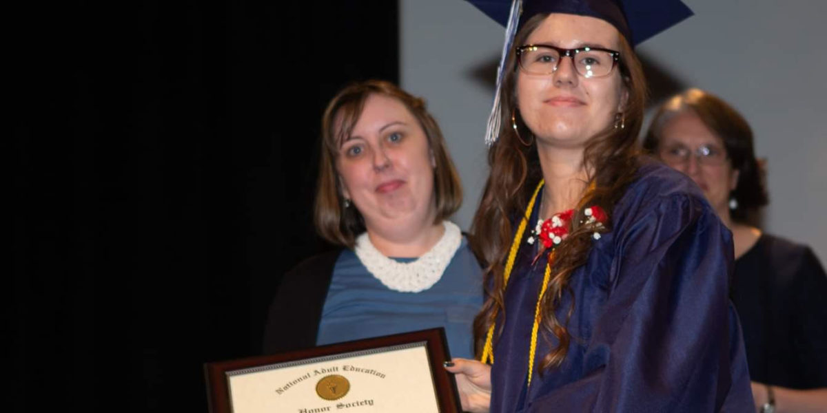 Young Woman in graduation attire with Adult Education Honor Society certificate