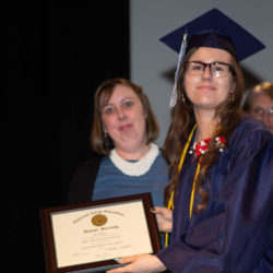 Young Woman in graduation attire with Adult Education Honor Society certificate