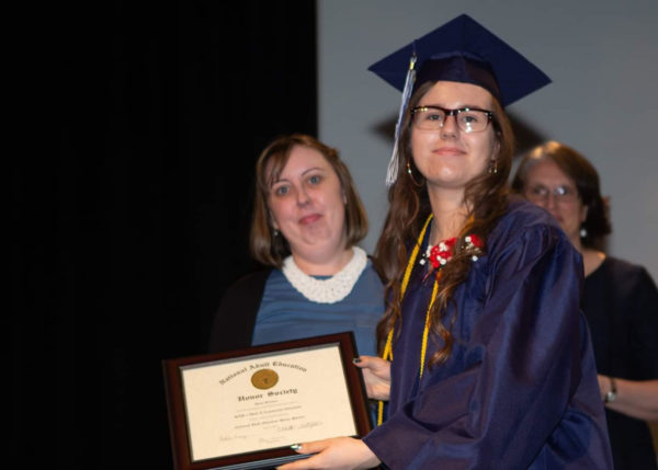 Young Woman in graduation attire with Adult Education Honor Society certificate
