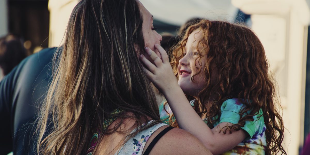 young girl with her hands on her mother's face