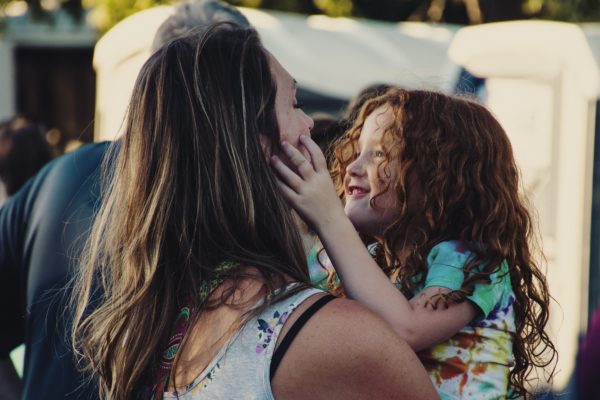 young girl with her hands on her mother's face