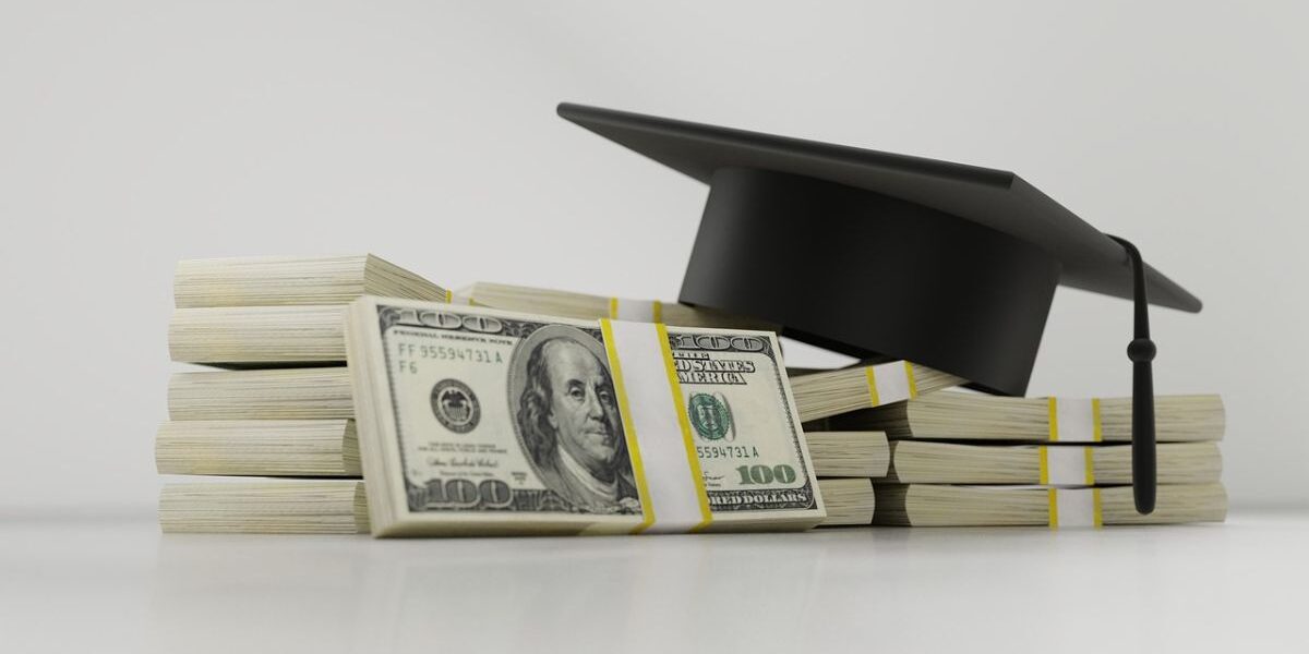 photo of graduation cap on top of stacks of American dollar bills