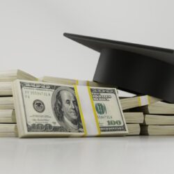 photo of graduation cap on top of stacks of American dollar bills