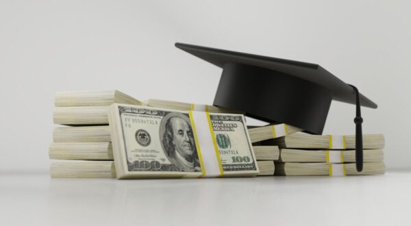 photo of graduation cap on top of stacks of American dollar bills