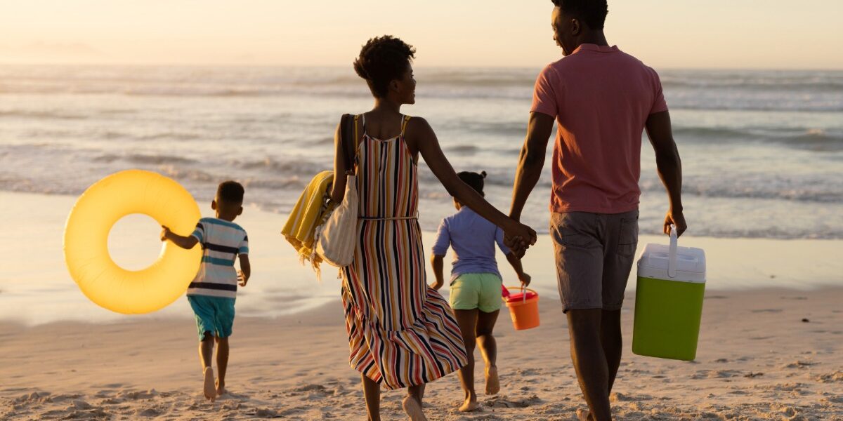 family of four on the beach with cooler and beach toys