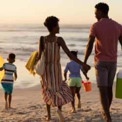 family of four on the beach with cooler and beach toys