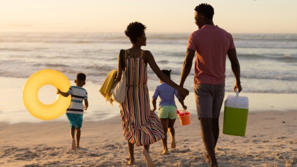family of four on the beach with cooler and beach toys